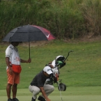 jay bayron setting his ball while his caddie taking cover in the rain